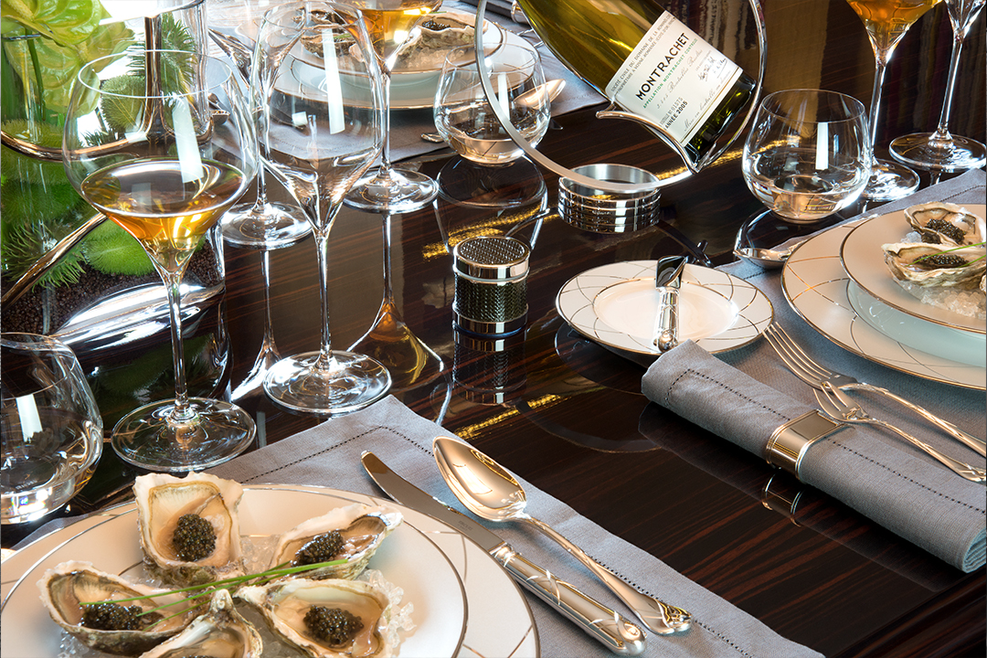 Produktfotografie eines gedeckten Tisches mit zahlreichen Wein- und Trinkgläsern, Besteck und reflektierenden Oberflächen.