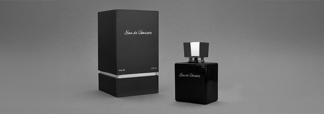 Schwarzer Parfumflakon mit passender Verpackung als hochwertige Produktfotografie auf grauem Hintergrund
