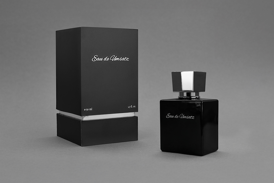Schwarzer Parfumflakon mit geschlossener Produktverpackung als gemeinsames Produktset auf grauem Hintergrund