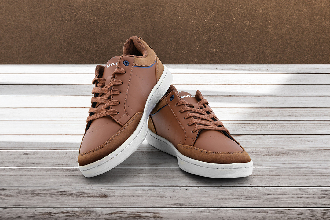 Produktfotografie eines braunen Sneaker-Paars auf heller Holzoberfläche vor neutralem Hintergrund
