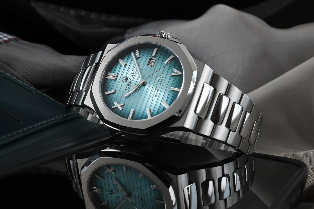 Produktfotografie einer Armbanduhr mit poliertem Metallgehäuse, türkisfarbenem Zifferblatt und kontrollierter Spiegelung auf Glas