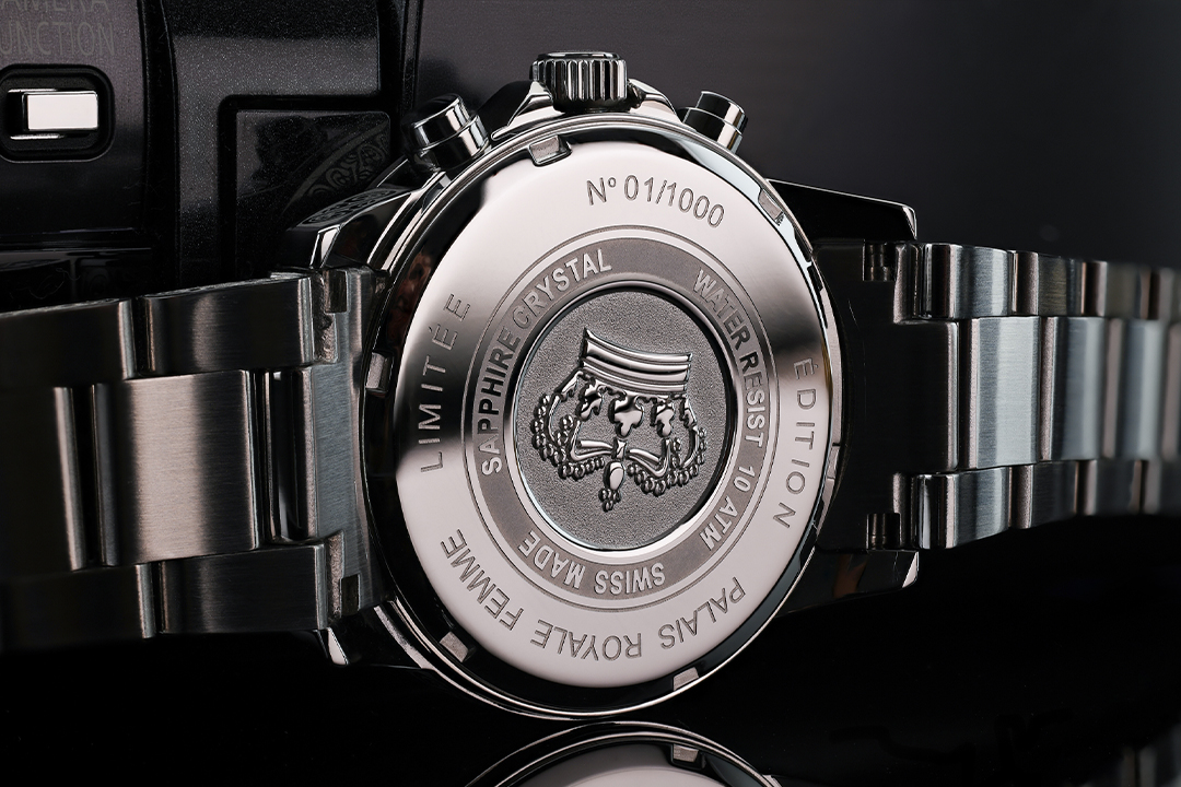 Detailaufnahme des polierten Edelstahl-Gehäusebodens einer Armbanduhr mit gravierter Beschriftung und Metallarmband.