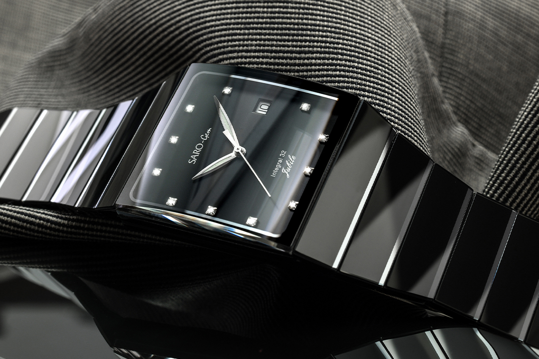 Produktfotografie einer schwarzen Armbanduhr mit hochglänzenden Glasflächen und facettiertem Armband.